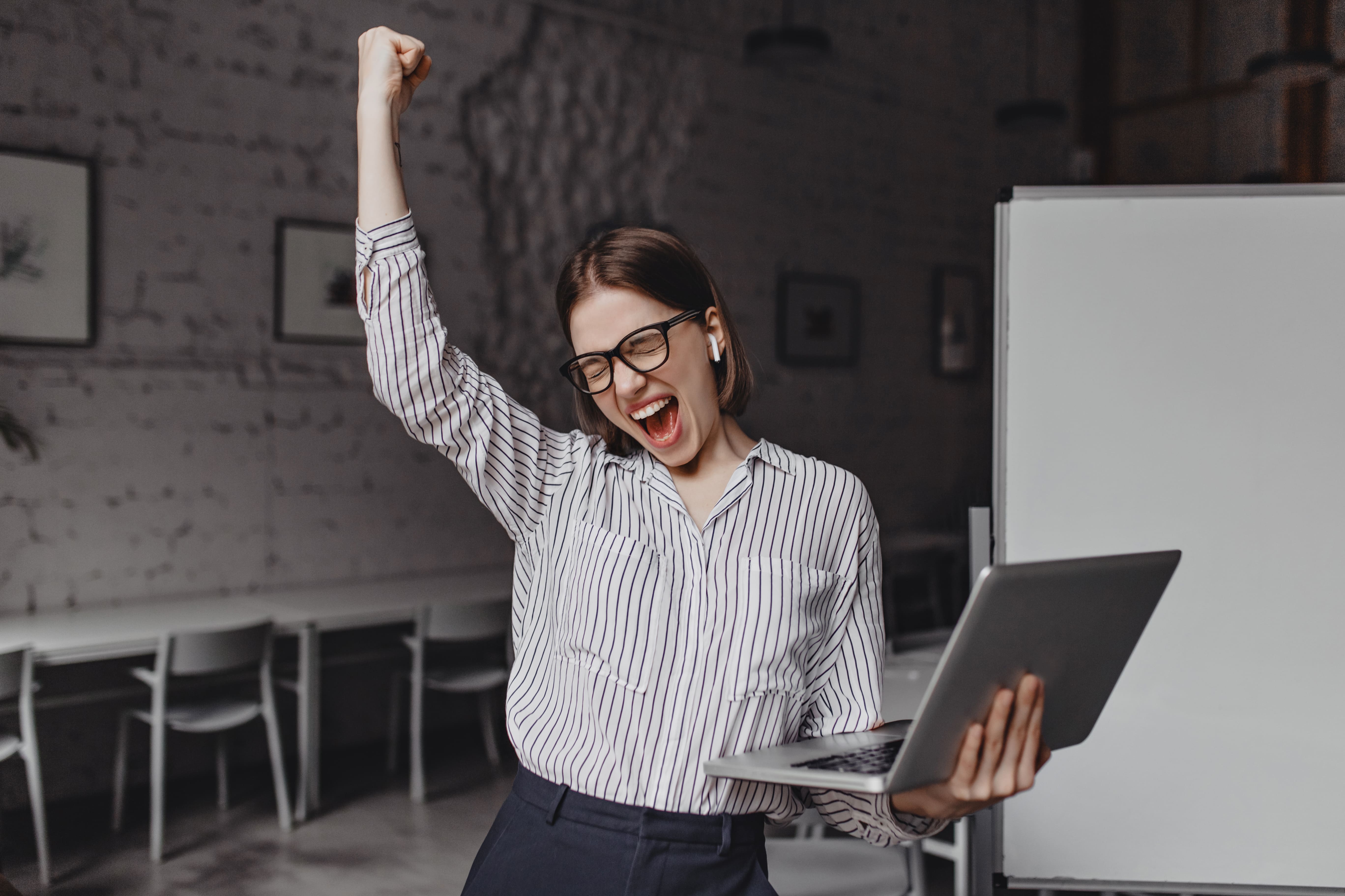 business-woman-with-laptop-in-hand-is-happy-with-success-portrait-of-woman-in-glasses-and-striped-blouse-enthusiastically-screaming-and-making-winning-gesture _1_