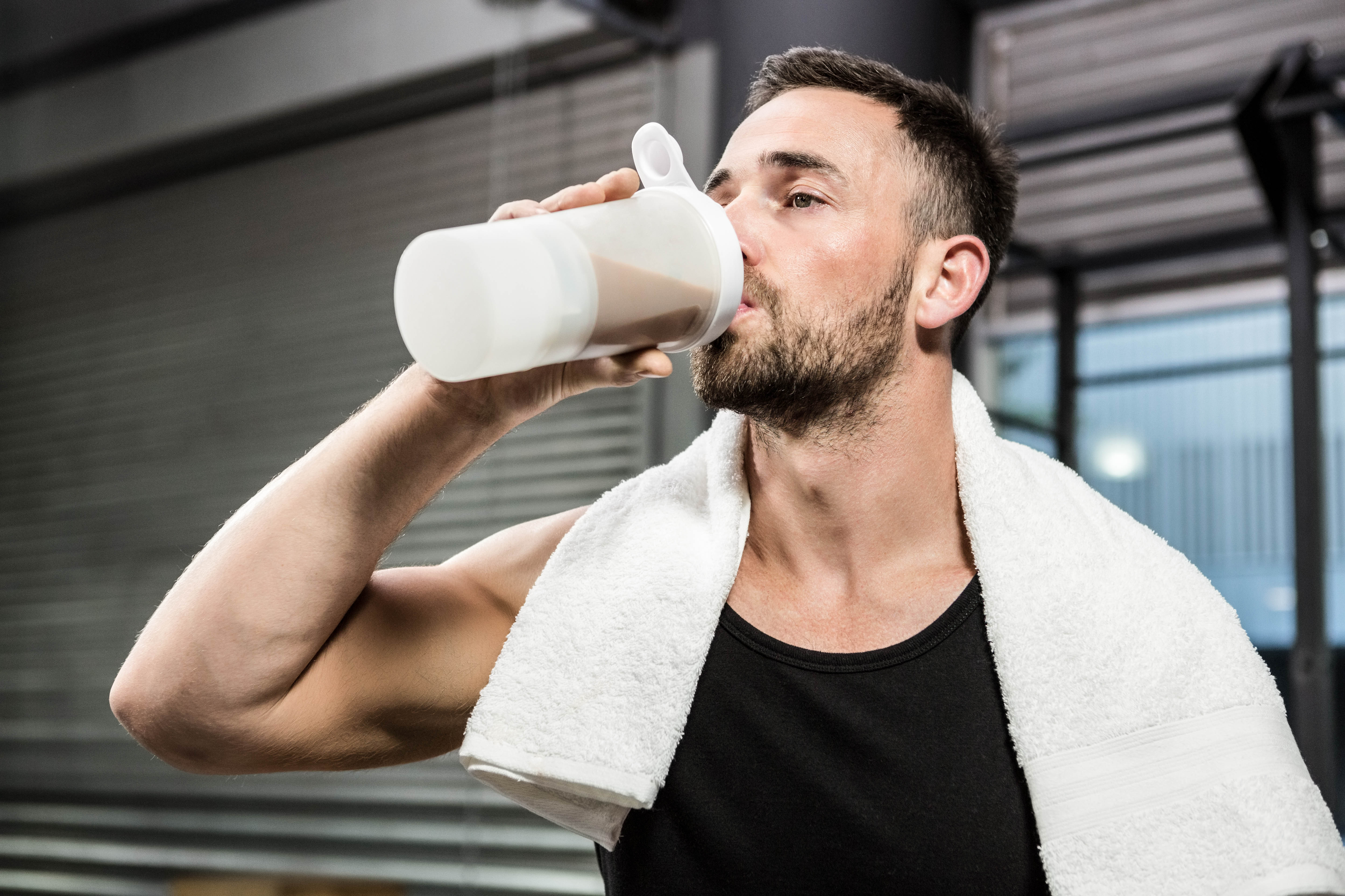 muscular-man-drinking-protein-shake-at-the-crossfit-gym